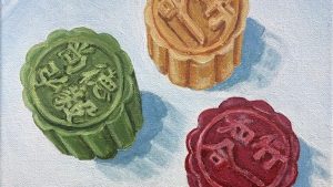 Three moon cakes in the colors red, green, and yellow, on a white background