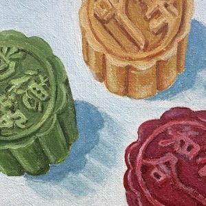 Three moon cakes in the colors red, green, and yellow, on a white background