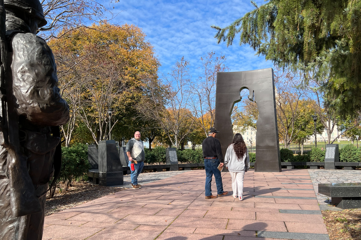 People stand in front of a veteran's memorial