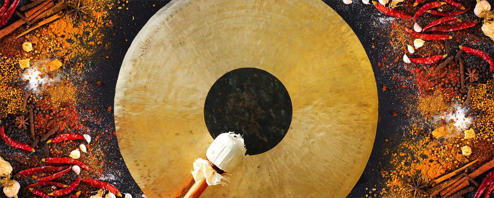 gong and mallet surrounded by South Asian spices