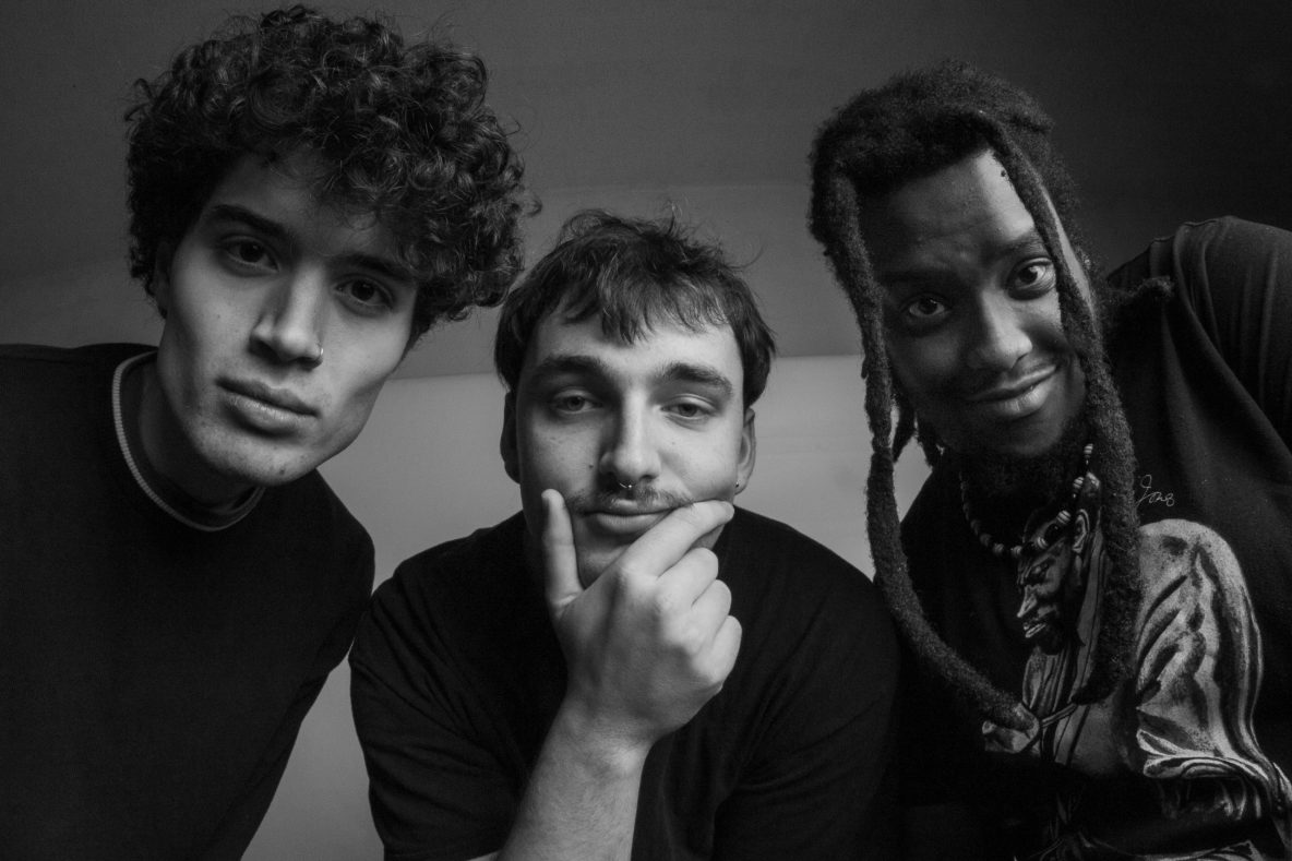 Black and white photo of three young jazz musicians leaning in towards the camera.