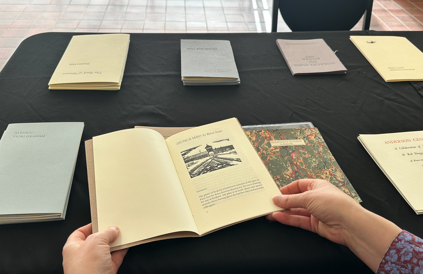 a pair of hands holding a hand-printed book of poetry by Barry Lopez