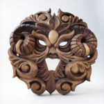 Carved wooden artwork with stylized foliage forming a face by Anya Kalk