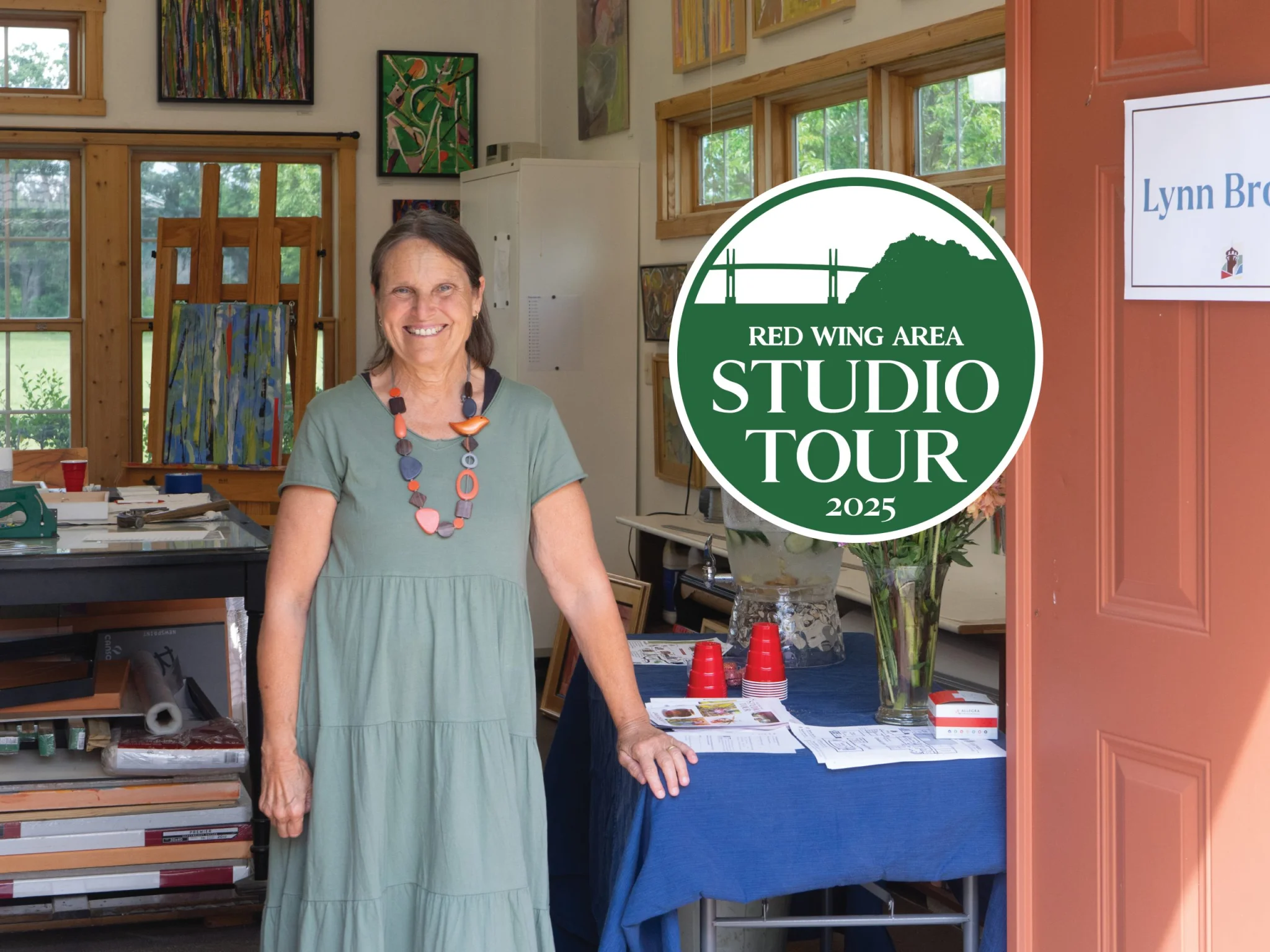 Red Wing Area Studio Tour 2025 logo in front of a smiling woman in her studio