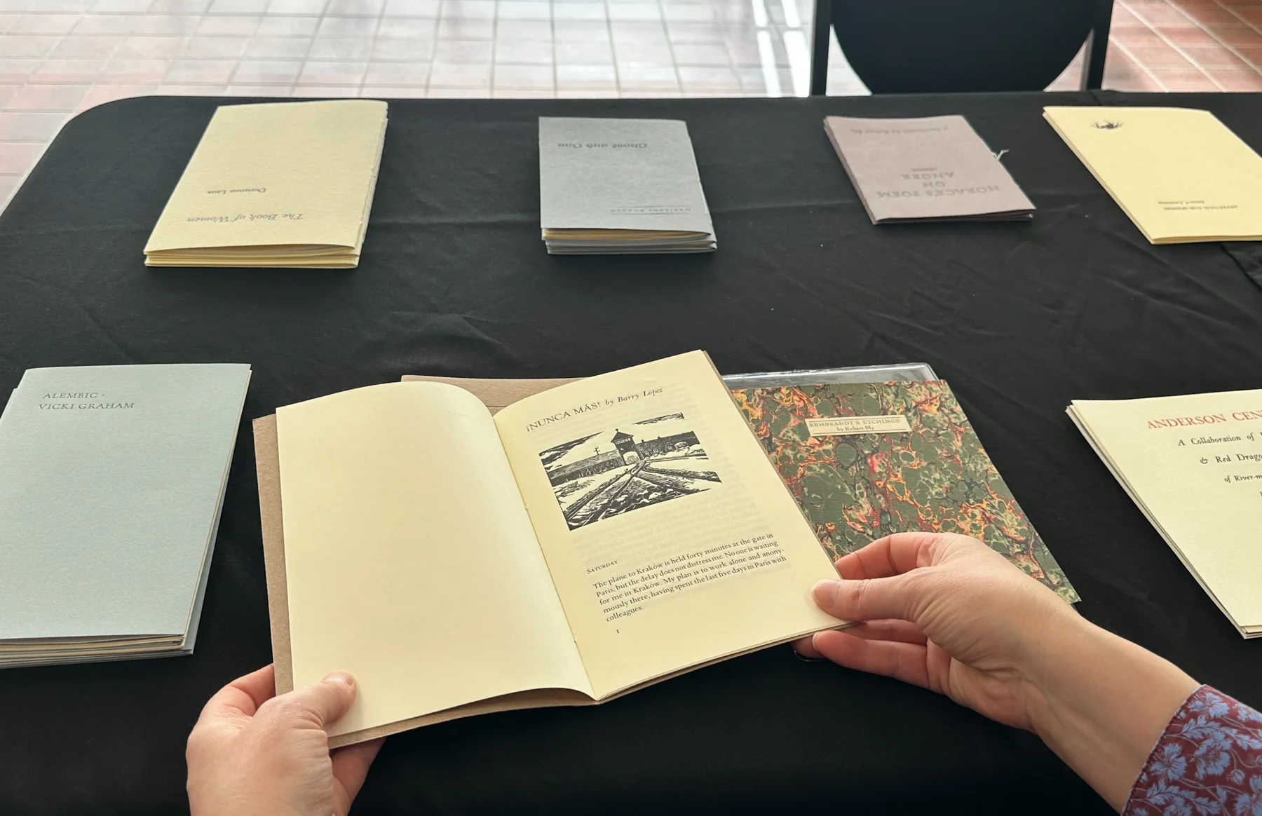 a pair of hands holding a hand-printed book of poetry by Barry Lopez
