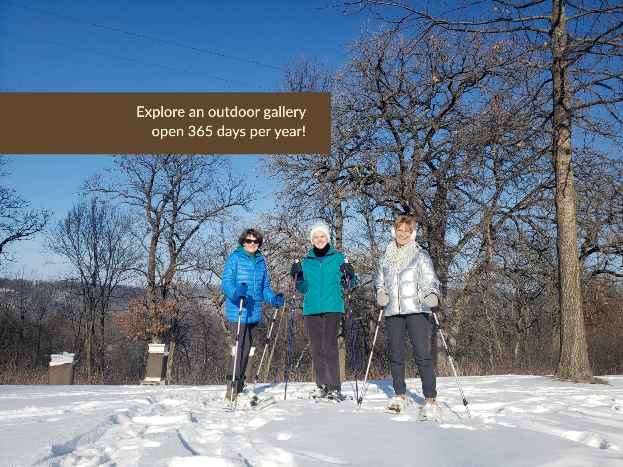 Three people with snowshoes and ski poles in a snowy landscape
