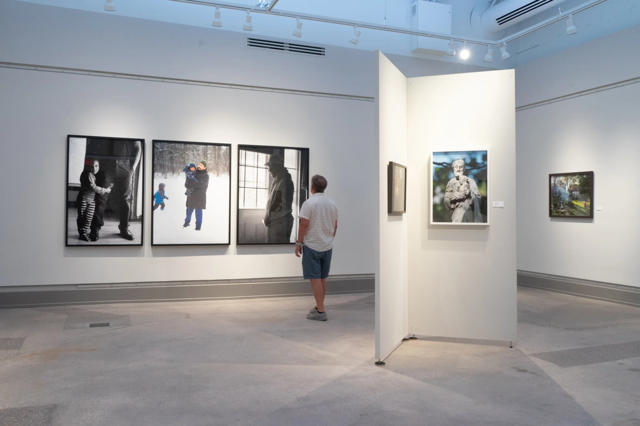 A person looks at large photos in Gallery One, a space with light gray walls, a concrete floor, and high ceilings.
